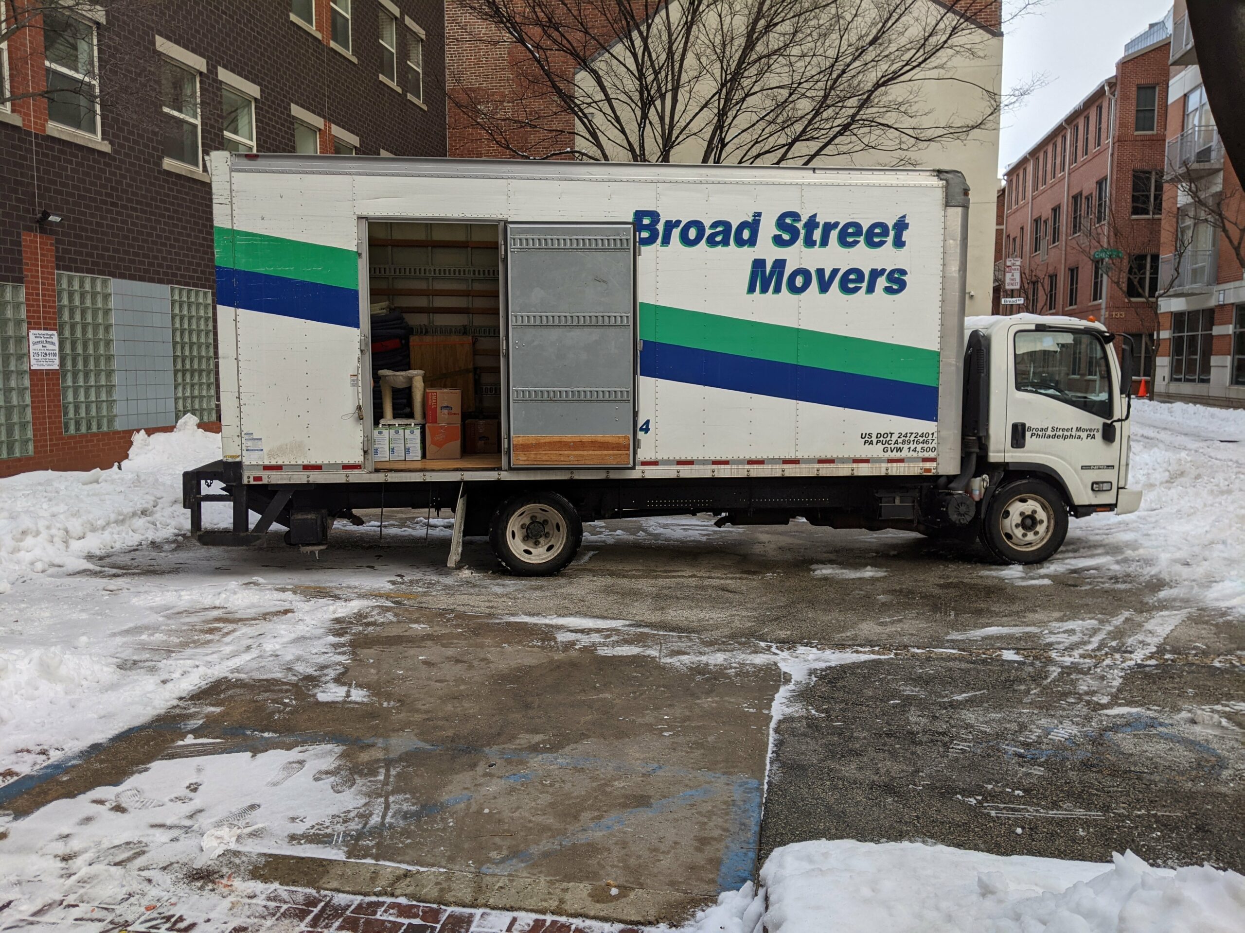 Broad Street Movers truck parked on a snowy street outside a city apartment building, showcasing our commitment to reliable service in any weather