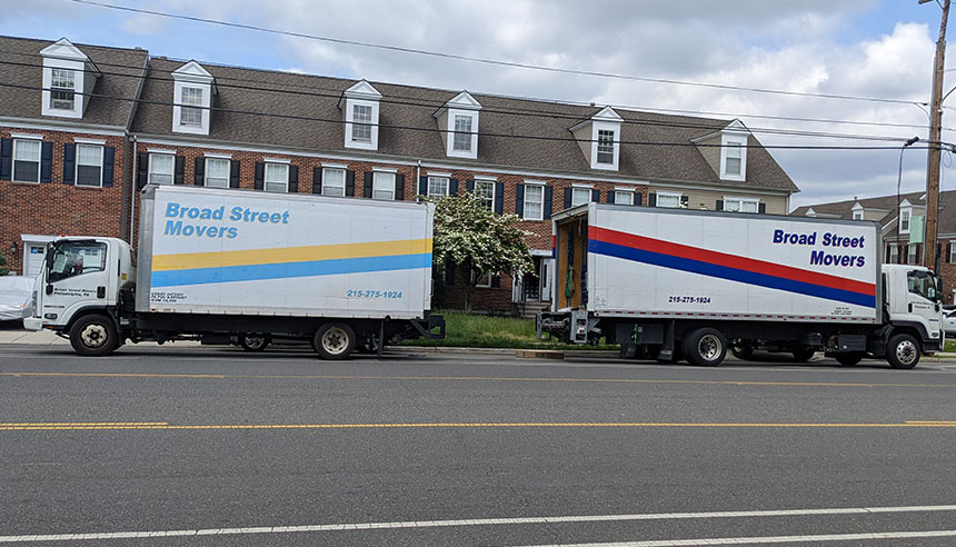 Two Broad Street Movers trucks parked outside an apartment complex in the Philly area are getting ready for a large local move in the city