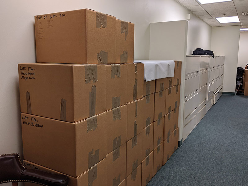 Completion of a Philadelphia corporate relocation as packed boxes are stacked safely next to file cabinets that movers are transporting.
