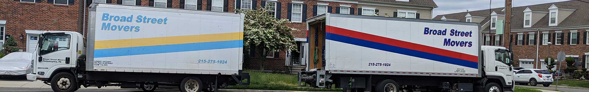 Two Broad Street Movers trucks parked back-to-back alongside a Philadelphia home where top-rated movers are packing a valued customer’s personal item.