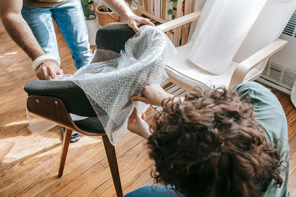 Homeowners are packing a nice chair in bubble wrap to protect it for their upcoming move in Philly.